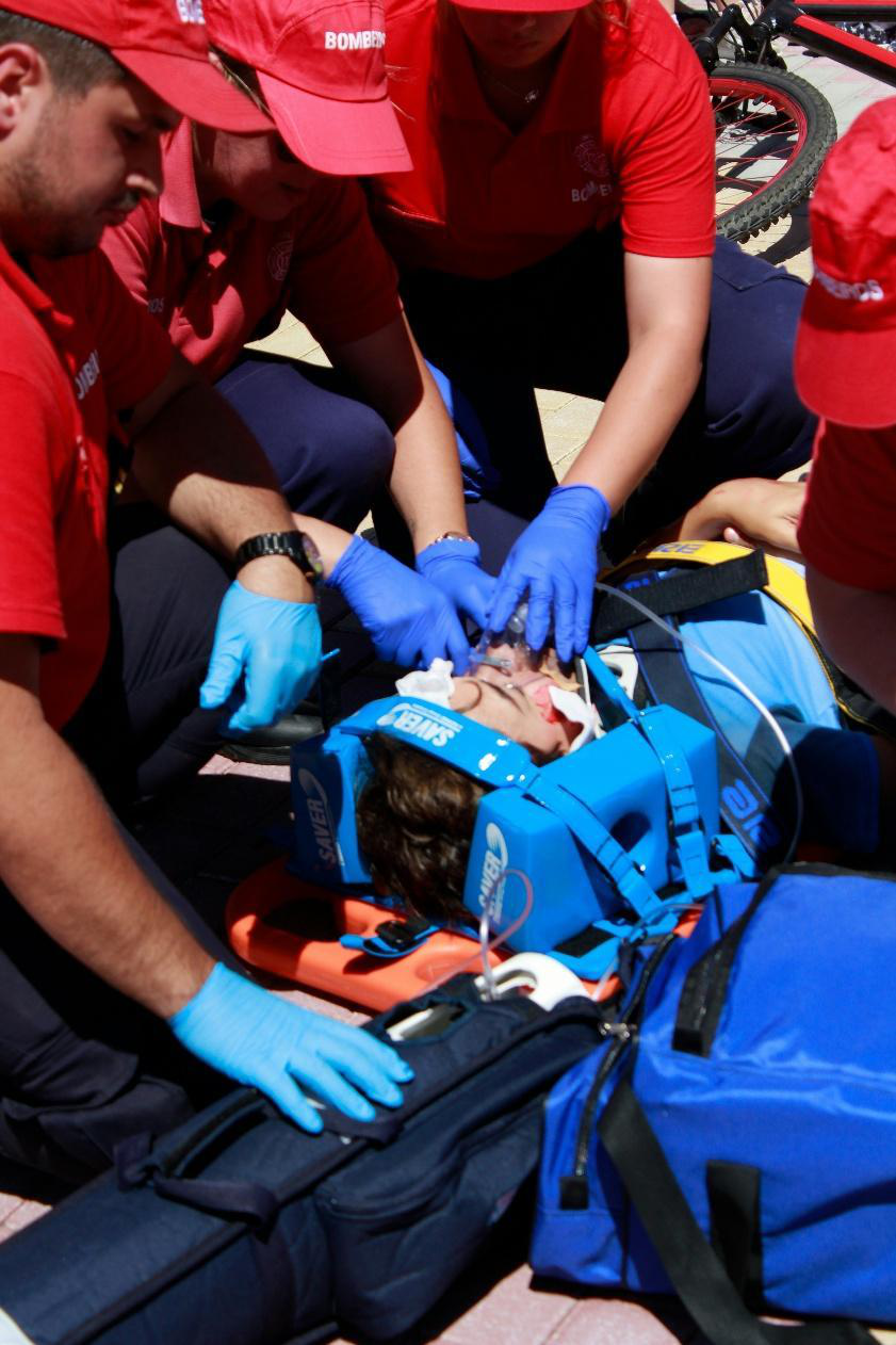 Emergency responders wearing gloves perform trauma care and airway stabilization during a hands-on medical training simulation.