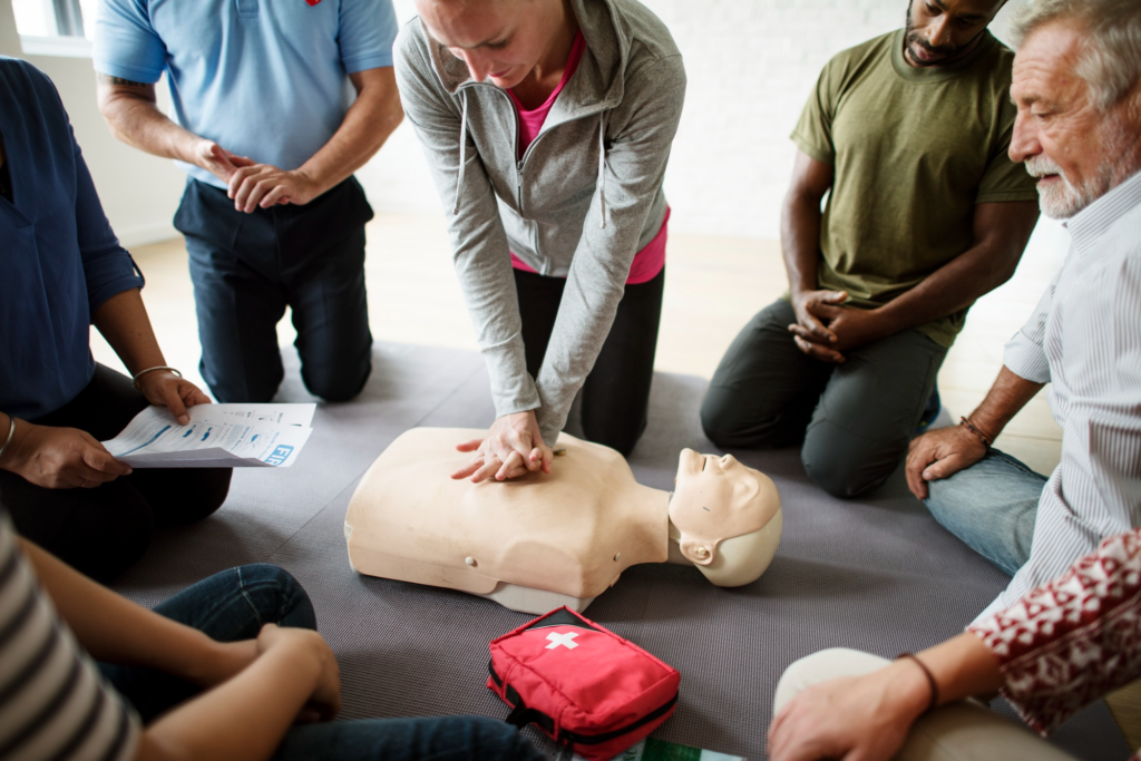 group of people attending CPR training class practicing chest compressions on manikins