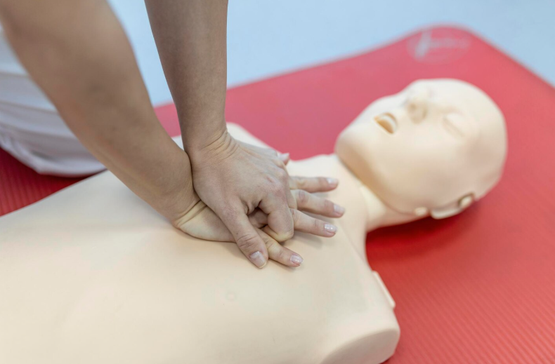 instructor demonstrating CPR chest compressions to students in first aid training class