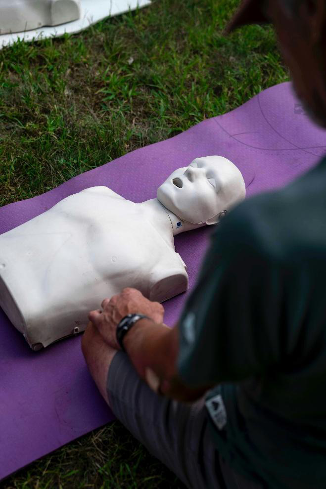 Student practices chest compressions on a CPR training manikin during an outdoor lifesaving skills session.