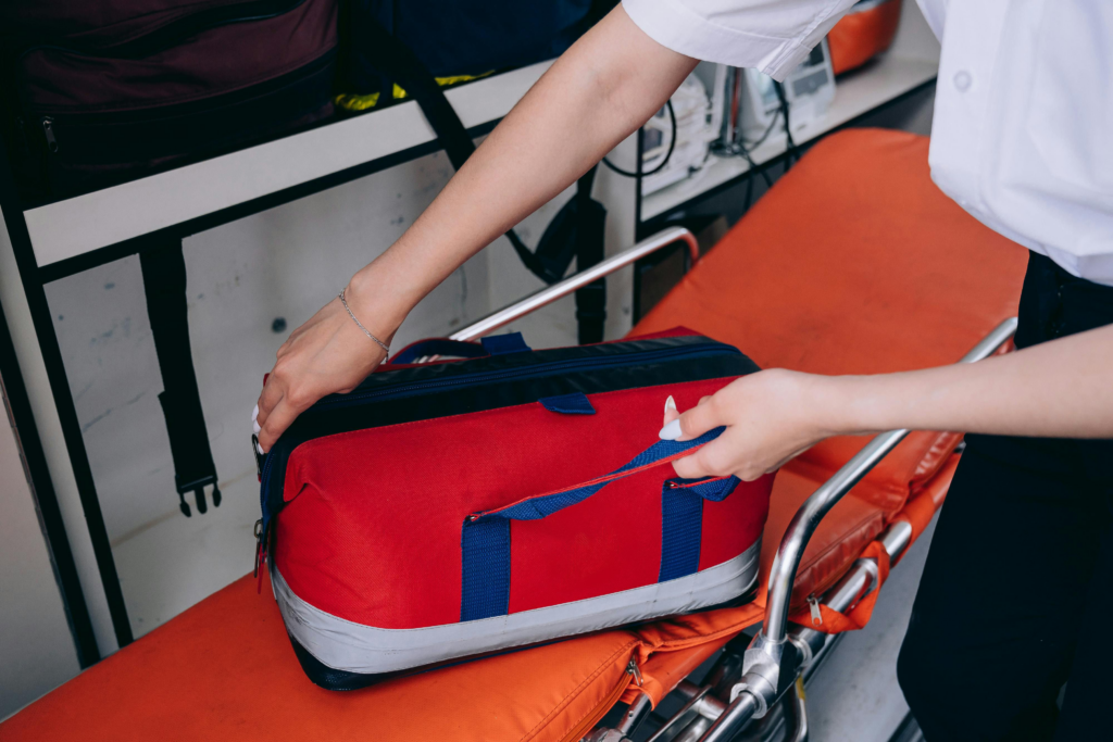 Healthcare worker reaches for an emergency medical bag on a stretcher.