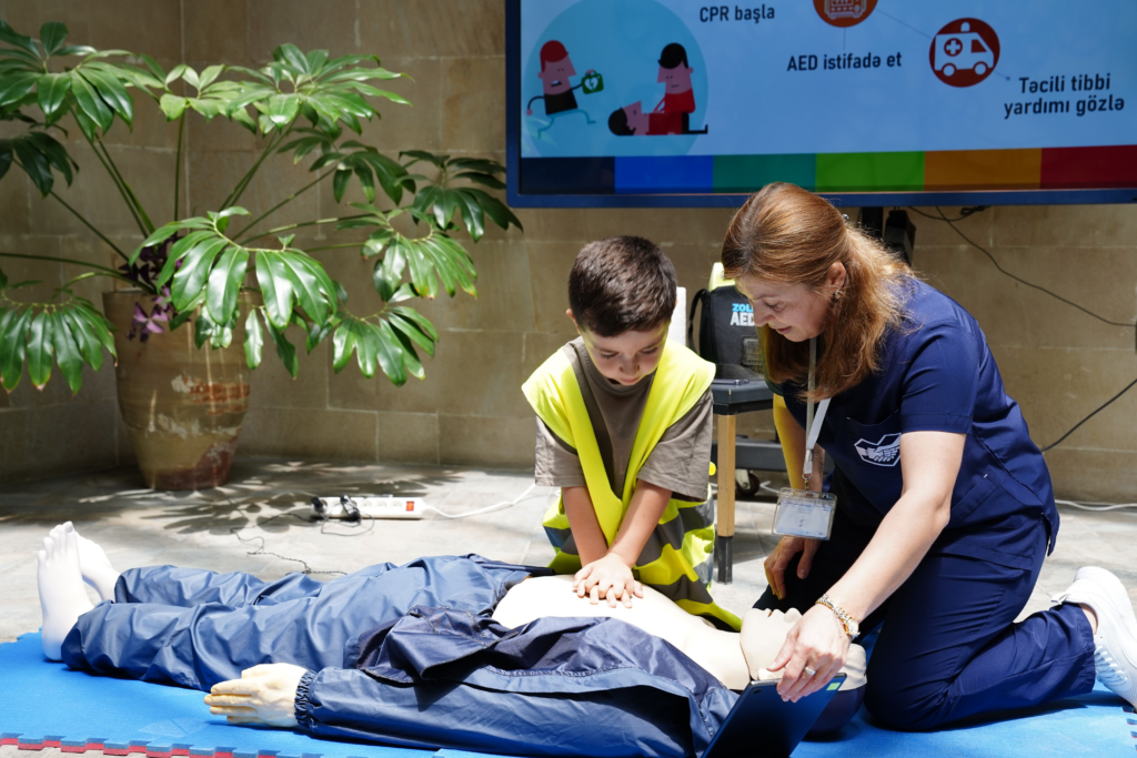 Child practices CPR on a training mannequin during a lifesaving skills session.
