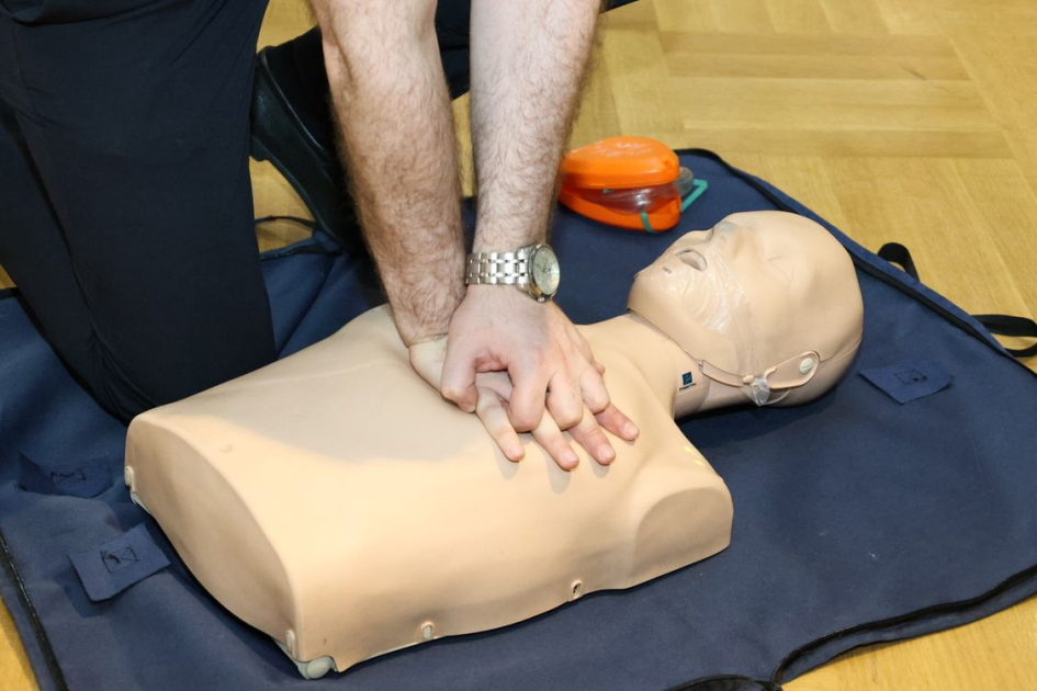 Person completing CPR and first aid training on a CPR mannequin during a certification class.