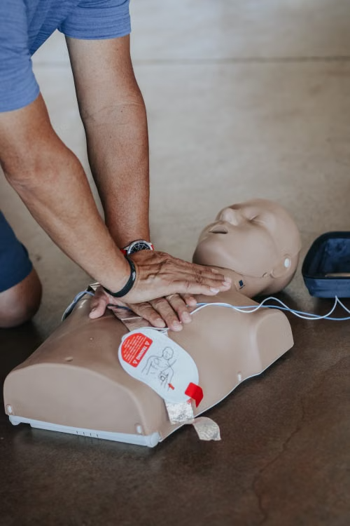 Student practicing CPR and first aid training while learning to recognize the signs of cardiac arrest.